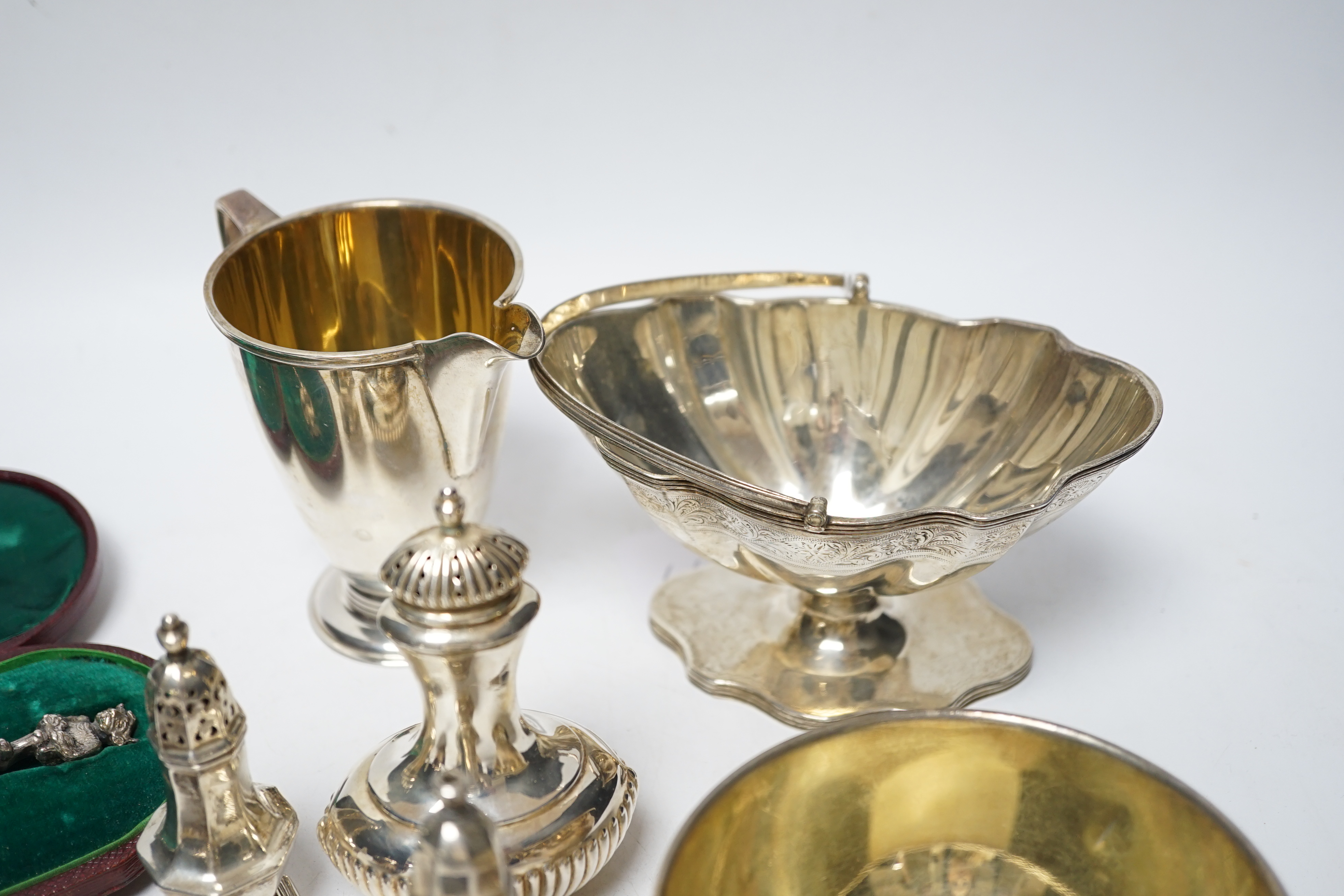 A group of small silver including Edwardian silver oval sugar basket, a modern silver cream jug and sugar bowl, five assorted condiments, a silver sifter spoon and a late Victorian scent bottle, 56mm.